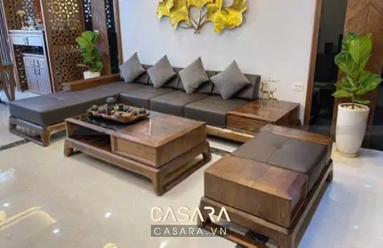Sofa gỗ óc chó chữ L tạo điểm chính khi tỷ lệ bàn trà và lối đi được giữ rõ.