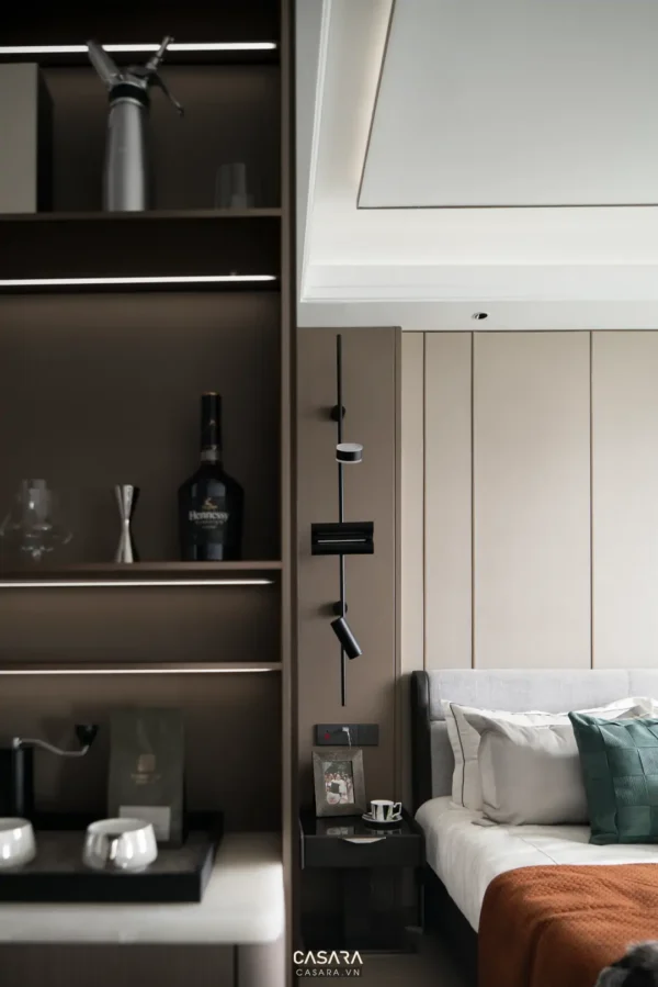 Góc phòng ngủ sang trọng với kệ rượu và đèn treo tường tinh tế.