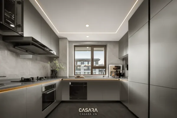 Nhà bếp hiện đại, tối giản với tông xám chủ đạo và ánh sáng vàng ấm áp.