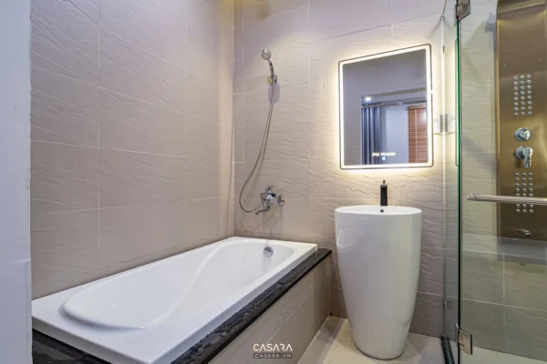 Phòng tắm hiện đại, sang trọng với bồn tắm trắng và gương lớn.