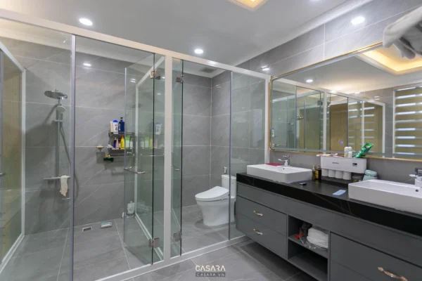 Phòng tắm hiện đại, sang trọng với vách kính và nội thất tối màu.
