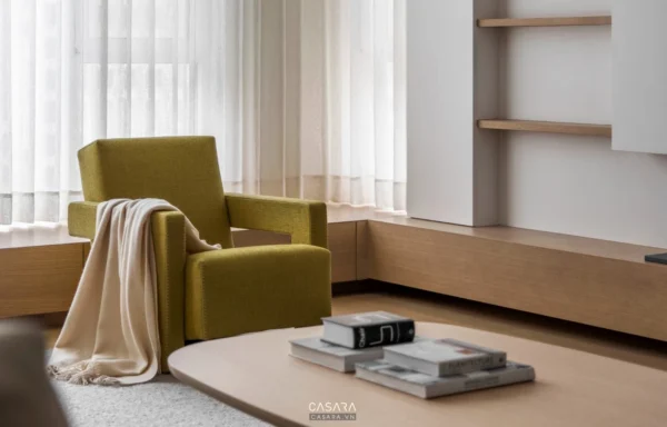 Phòng khách tối giản với ghế bọc nhung xanh và rèm trắng tinh tế.