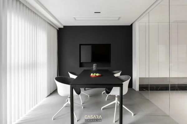 Phòng ăn tối giản với TV, bàn đen và ghế trắng hiện đại.