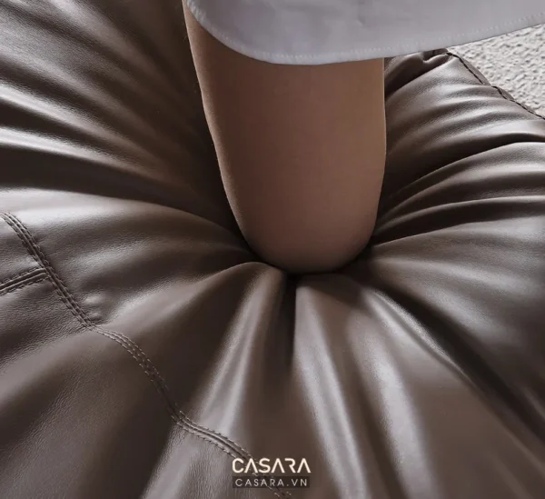 Ghế sofa da màu nâu với thiết kế đệm lõm độc đáo, hiện đại.