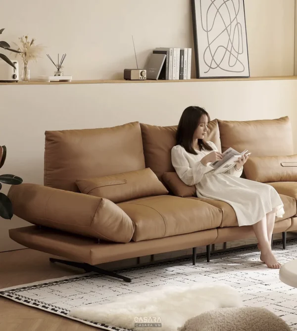 Cô gái thư giãn đọc sách trên chiếc sofa da màu nâu ấm cúng.