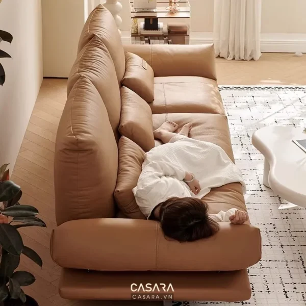 Ghế sofa da màu nâu nhạt, người đang nằm thư giãn trên ghế.