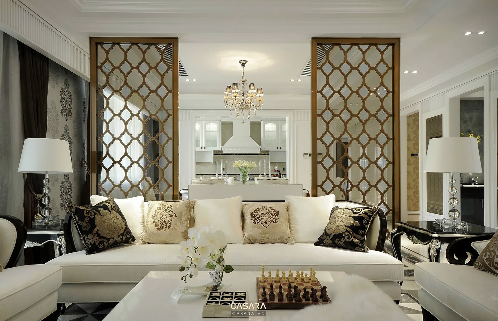 Phòng khách luxury có vách trang trí kim loại, sofa sáng và đèn bàn đối xứng