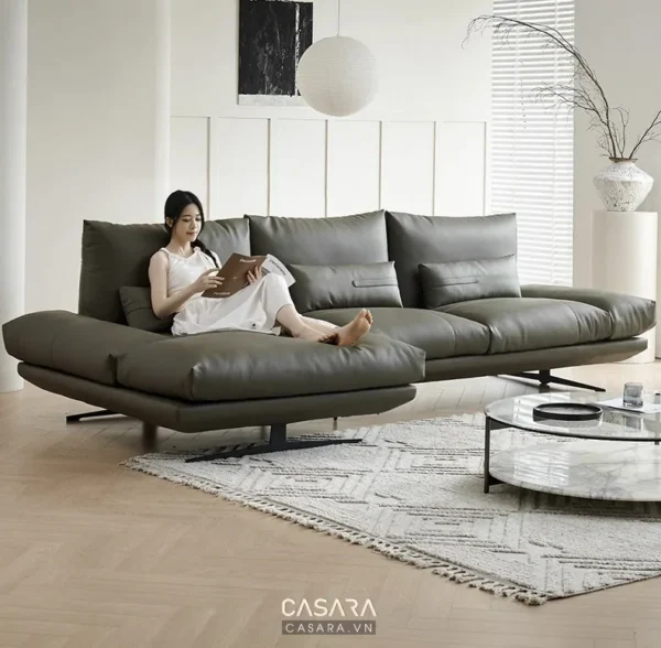 Phòng khách hiện đại với ghế sofa da lớn màu xám và cô gái đang đọc sách.