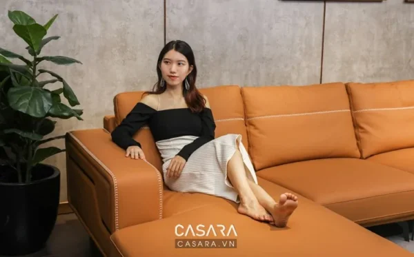 Cô gái trẻ thư giãn trên chiếc sofa da màu cam hiện đại.