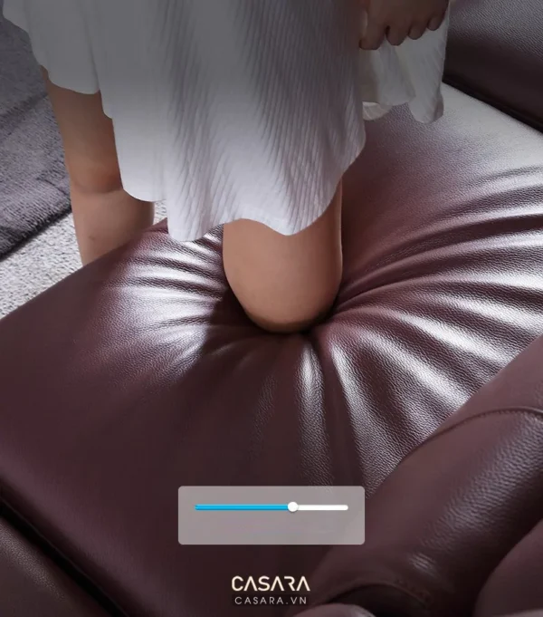 Chân phụ nữ thư giãn trên giường da màu burgundy sang trọng.