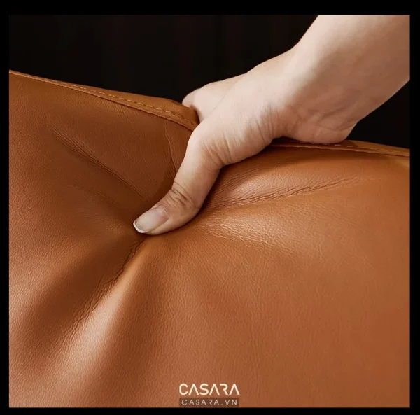 Bàn tay chạm nhẹ vào bề mặt da mềm mại, màu nâu ấm áp.