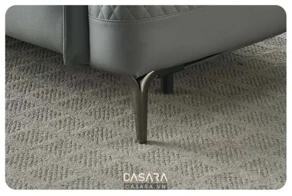 Góc nhìn cận cảnh chân ghế sofa da xám hiện đại trên thảm.
