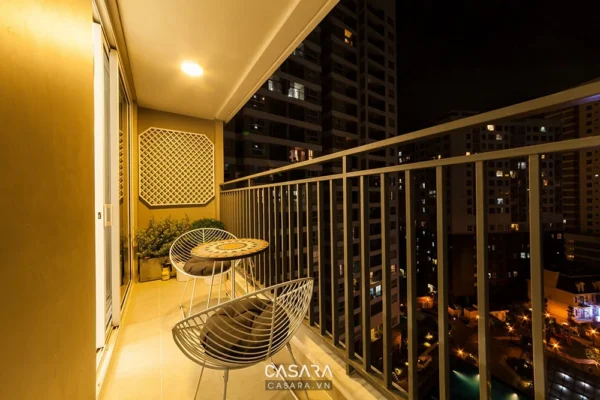 Ban công nhỏ ấm cúng với nội thất kim loại và ánh đèn vàng dịu.