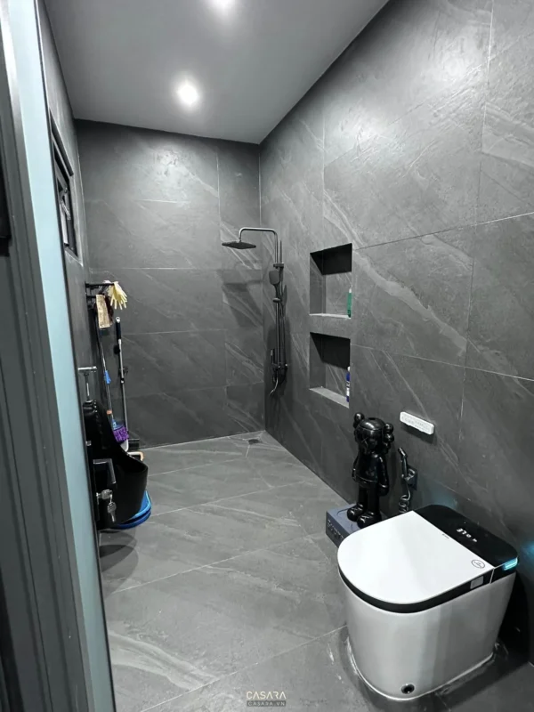 Phòng tắm hiện đại với gạch tối màu và thiết bị vệ sinh thông minh.