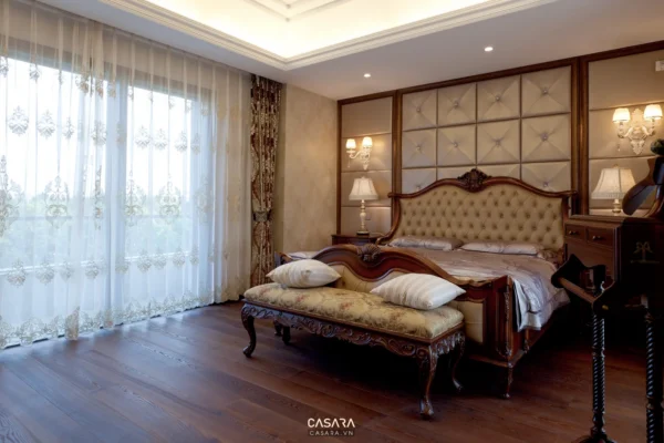 Phòng ngủ sang trọng với giường lớn, nội thất gỗ và rèm cửa trắng tinh tế.