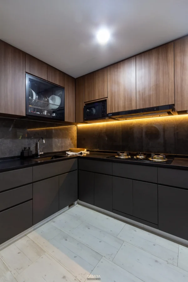 Góc bếp hiện đại, sang trọng với tủ gỗ và đèn vàng ấm áp.