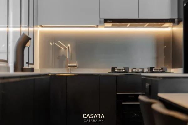 Phòng bếp hiện đại, tối giản với ánh sáng vàng ấm áp.