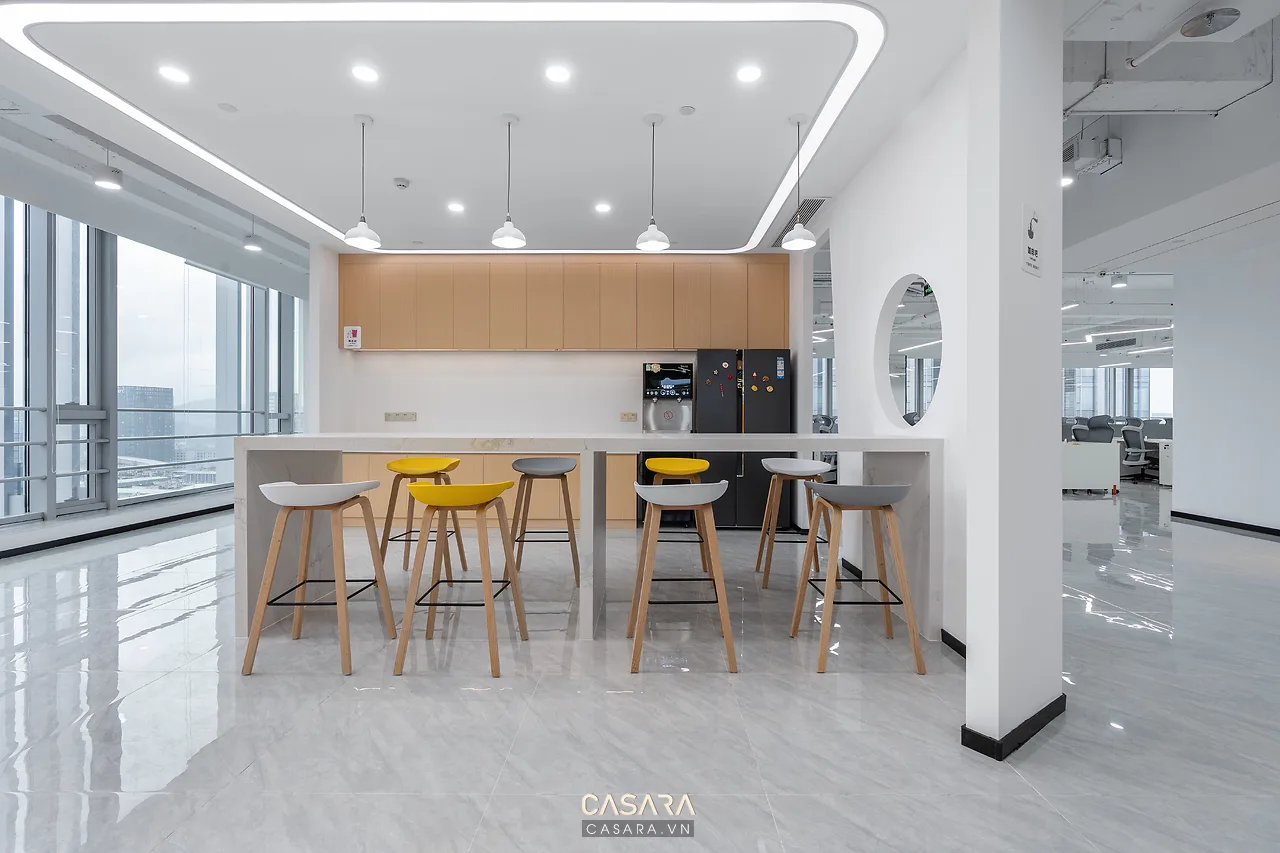 thiết kế văn phòng có pantry nhỏ bàn bar ghế cao tủ gỗ cây xanh và ánh sáng ấm