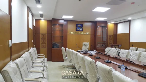 Phòng họp trang trọng với bàn dài và ghế bọc trắng lịch sự.