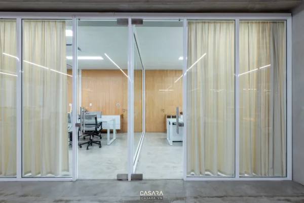 Cửa kính lùa hiện đại, nhìn vào không gian văn phòng sáng sủa.