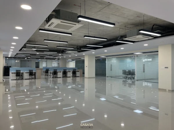 Văn phòng sau thi công có bàn họp dài, ghế làm việc, hệ trần và ánh sáng hoàn thiện