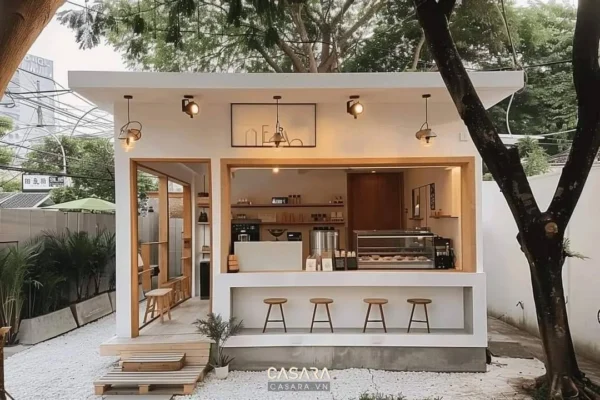 Mặt tiền quán cafe nhỏ có quầy mở, ghế cao và khoảng ngồi ngoài trời