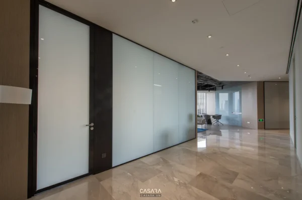 Hành lang văn phòng hiện đại với vách kính mờ và sàn đá bóng loáng.