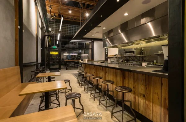 Không gian quán ăn hiện đại với quầy bar và khu vực chỗ ngồi gỗ.