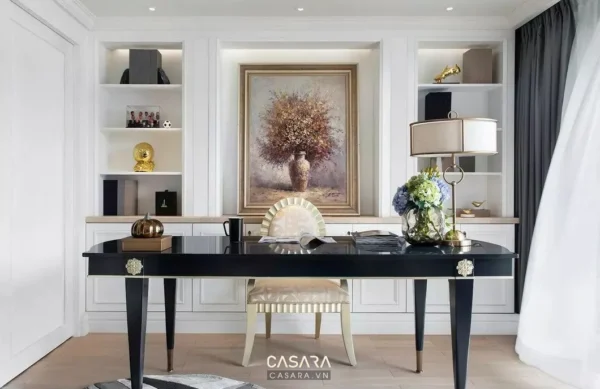 Góc làm việc sang trọng với tranh, sách và đèn bàn trang trí.