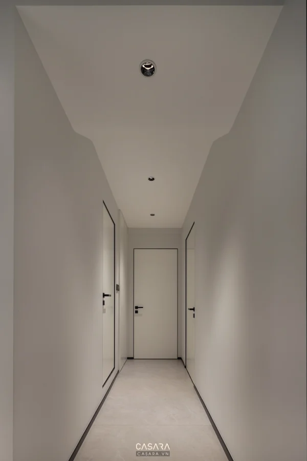 Hành lang dài, trắng sáng, tối giản với các cửa trắng tinh tế.