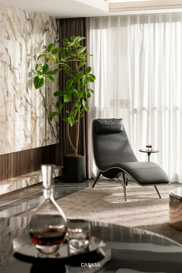 Góc phòng khách sang trọng với ghế đen và cây xanh.