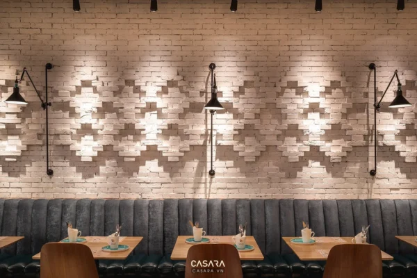 Không gian quán cà phê hiện đại với tường gạch trắng và đèn chiếu sáng.
