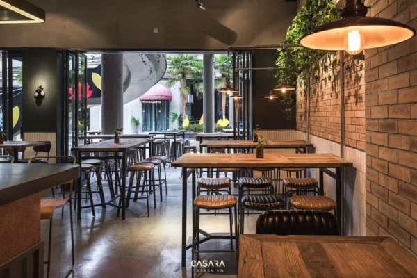 Không gian quán cafe hiện đại với tường gạch và cây xanh.