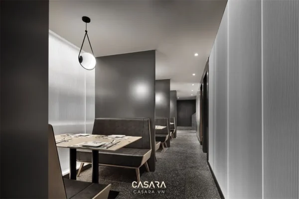 Nội thất nhà hàng hiện đại với tông màu xám đen chủ đạo, ánh sáng dịu nhẹ.