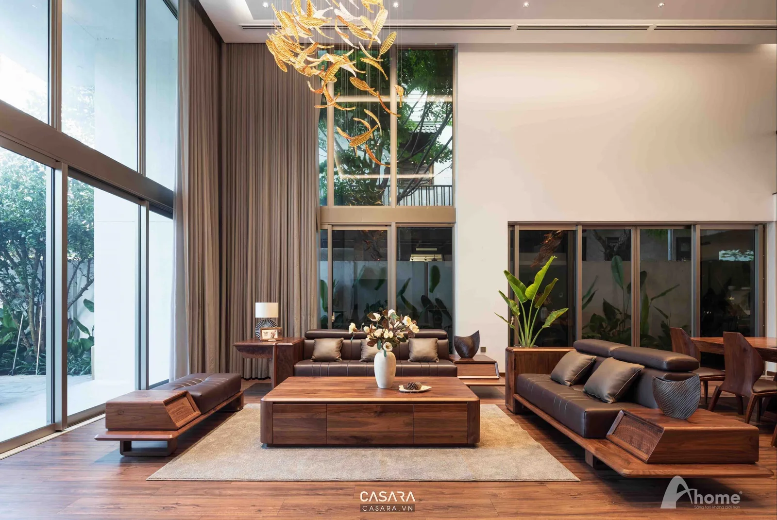 Không gian nghỉ dưỡng có sofa, bàn trà, cửa kính lớn và vật liệu gỗ ấm