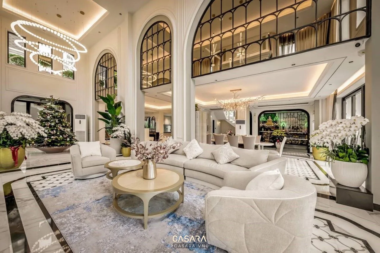 Phòng khách cao cấp có sofa trắng, vòm lớn, đèn chùm và cây trang trí