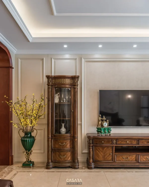 Phòng khách sang trọng với tủ trưng bày cổ điển và hoa mai tươi.