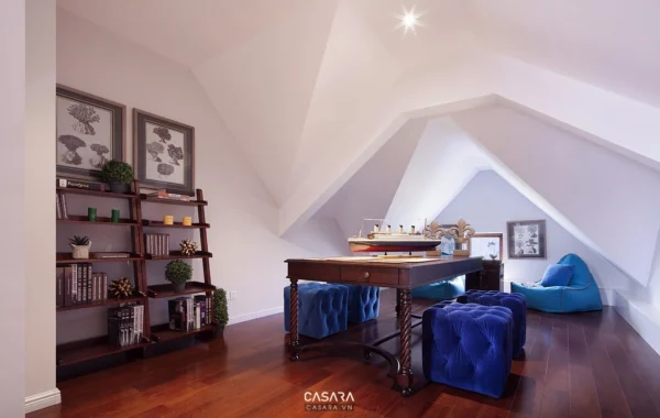 Phòng gác mái ấm cúng với bàn bida, kệ sách và ghế sofa xanh.