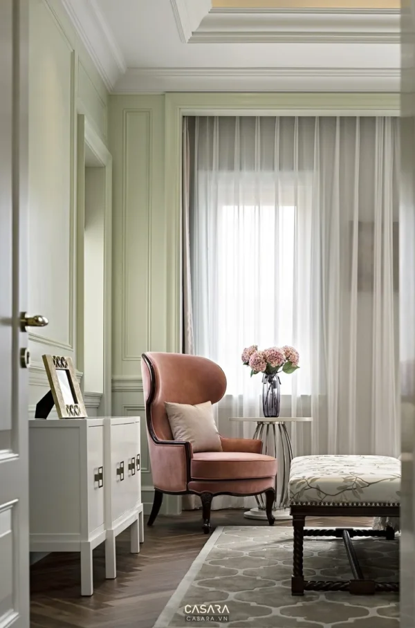 Góc phòng khách trang nhã với ghế bành nâu và tủ trắng tinh tế.