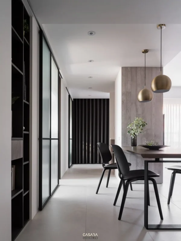 Phòng ăn tối giản, hiện đại với tông đen–trắng chủ đạo, ánh sáng vàng ấm.