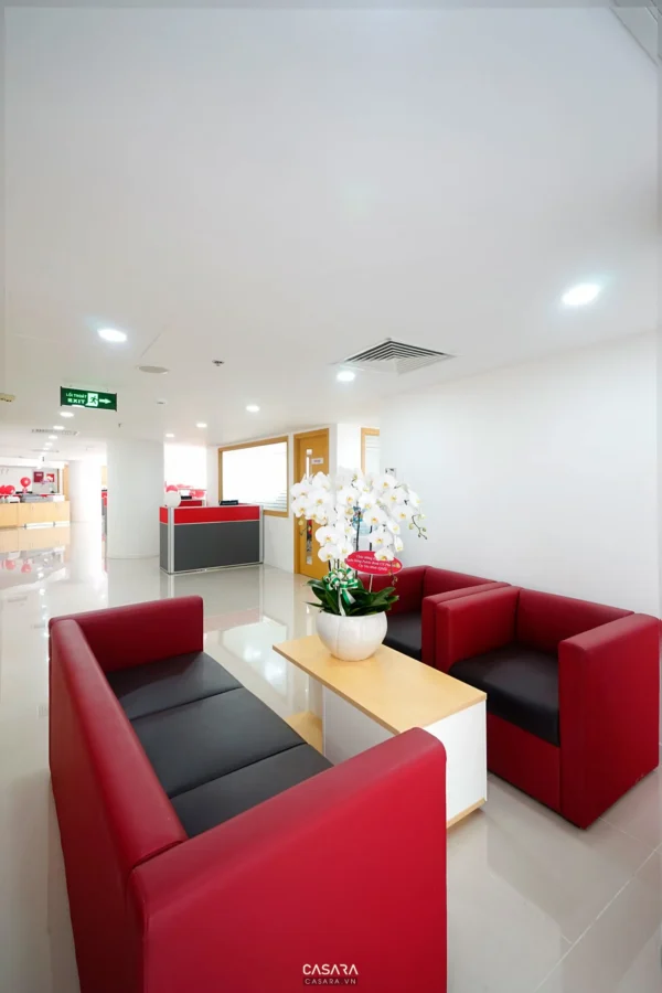 Khu vực lễ tân rộng rãi, hiện đại với ghế sofa đỏ nổi bật.