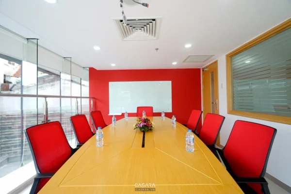 Phòng họp hiện đại với bàn gỗ dài và ghế đỏ nổi bật.