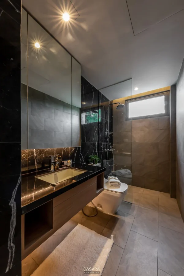 Phòng tắm hiện đại, sang trọng với đá đen và ánh sáng ấm áp.