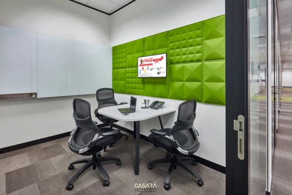 Phòng họp nhỏ với tường xanh, bàn trắng và ghế xoay hiện đại.