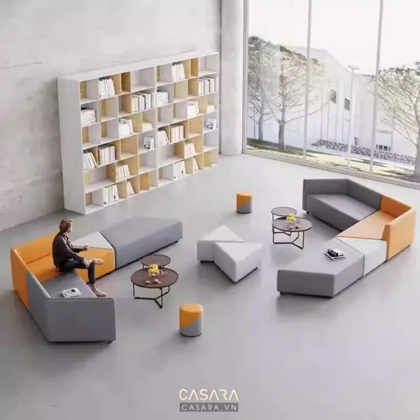 Phòng khách hiện đại với kệ sách lớn và bộ sofa màu cam, xám.