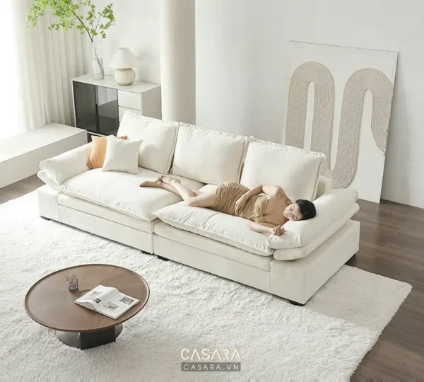 Một người phụ nữ nằm trên chiếc sofa trắng lớn.