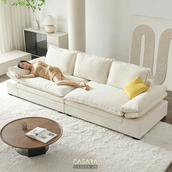 Một người nằm dài trên chiếc sofa trắng lớn.