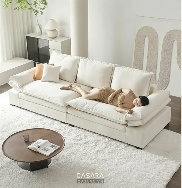 Một người nằm thư giãn trên chiếc sofa trắng lớn.