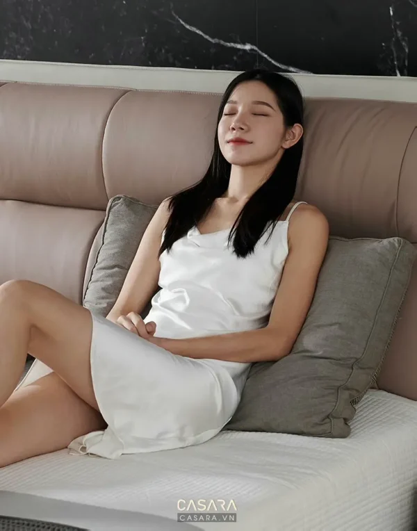 Cô gái trẻ thư giãn trên chiếc sofa êm ái, tận hưởng sự yên bình.