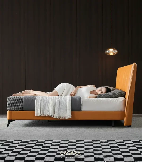 Người phụ nữ thư giãn trên chiếc giường màu cam ấm cúng, sang trọng.